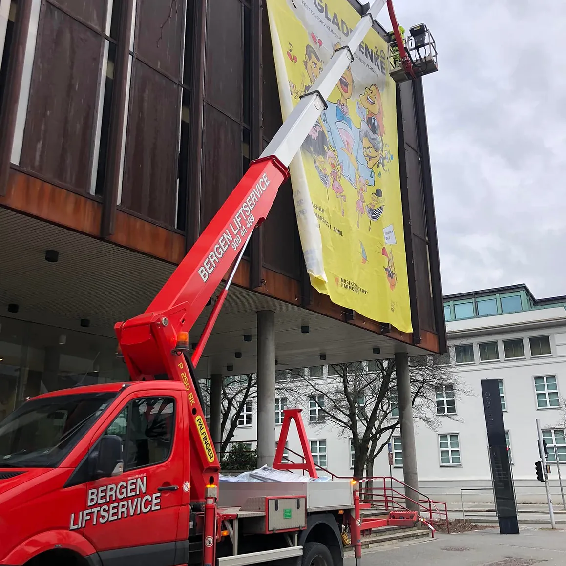 Rød lift henger opp stor plakat